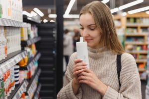 Shopping Cosmetics Woman Smelling Bottle Of Shampoo In Store - Recuperação de Impostos | Planrec Gestão Tributária